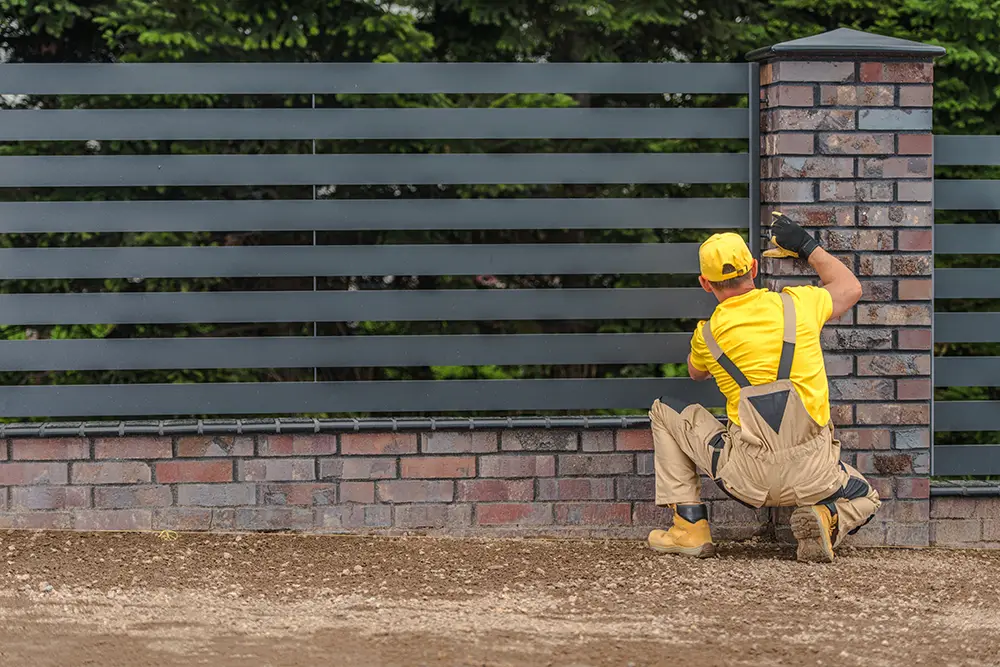 Technician repairing a damaged privacy fence with new wooden boards